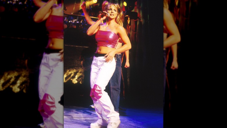 Britney Spears sur scène dans un haut tube rose vif et un pantalon cargo blanc.