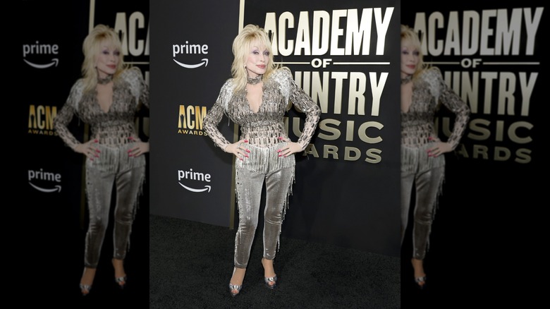 Dolly Parton assiste aux Academy of Country Music Awards 2023 portant un ensemble haut et pantalon ornés de bijoux en argent