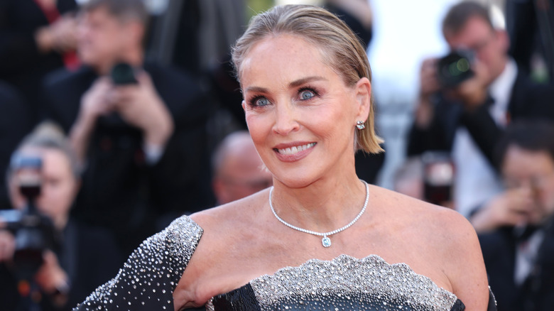 Sharon Stone portant une robe et un châle cloutés de strass ainsi qu'un collier à pendentif en diamant lors d'un événement sur le tapis rouge