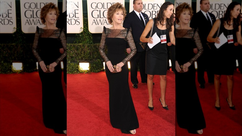 Jane Fonda posant sur le tapis rouge des Golden Globes vêtue d'une longue robe noire avec des manches et des épaules détaillées.