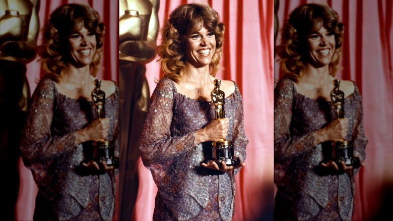 Jane Fonda posant avec son Oscar, vêtue d'une robe violette fluide et de cheveux bouclés.