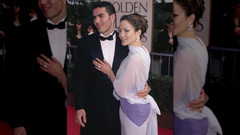 Jennifer Lopez dans une robe blanche et lilas et un chignon haut avec Ojani Noa avec un smoking noir.