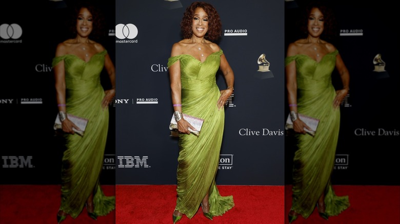 Gayle King posant sur le tapis rouge, la main sur la hanche, vêtue d'une robe chartreuse fluide à épaules dénudées.
