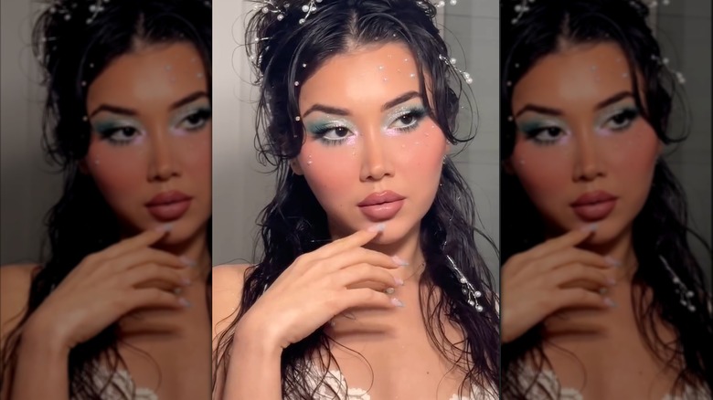 Une femme portant un maquillage sirène, avec un fard à paupières bleu-vert et un fard à joues ensoleillé