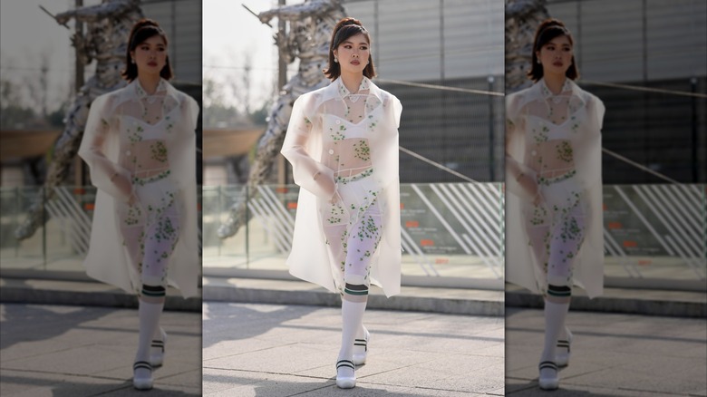 Une femme porte un manteau blanc transparent.