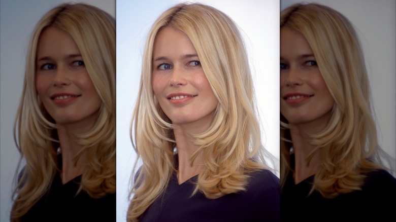Claudia Schiffer souriant légèrement, la tête tournée sur le côté, les cheveux blonds détachés.
