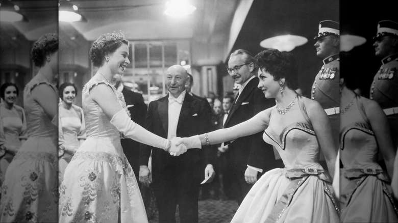 Gina Lollobrigida portant une robe dos nu décolletée serrant la main de la reine Elizabeth.