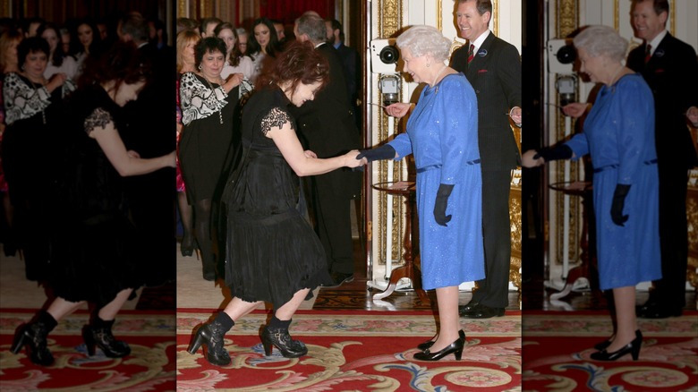 Helena Bonham Carter faisant la révérence dans une robe noire et des bottes serrant la main de la reine Elizabeth. portant une robe bleue.