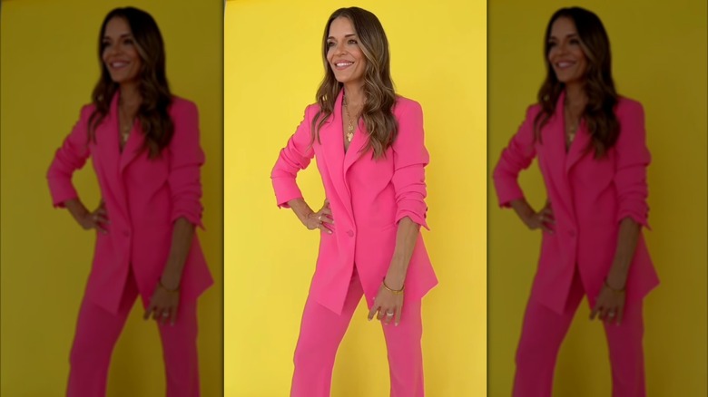Sabrina Soto posant dans un costume rose devant un fond jaune.