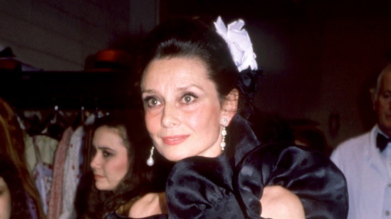 Audrey Hepburn avec un chignon et une fleur blanche dans les cheveux