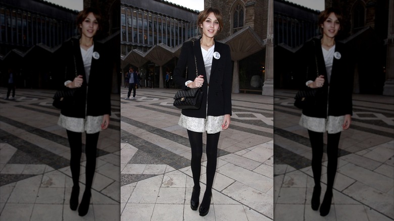Alexa Chung a été photographiée portant une veste noire, une robe blanche, des collants noirs et des chaussures noires en extérieur.