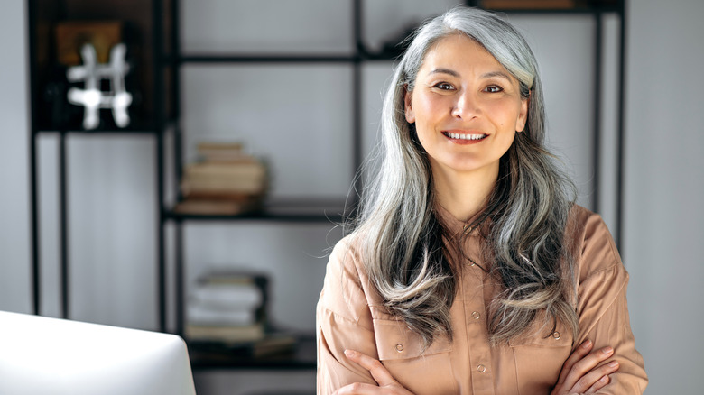 Une femme sourit aux cheveux gris bouclés