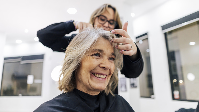 Une femme se fait soigner les cheveux gris dans un salon
