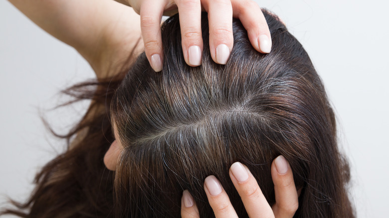 Une femme tire sur ses cheveux gris-brun