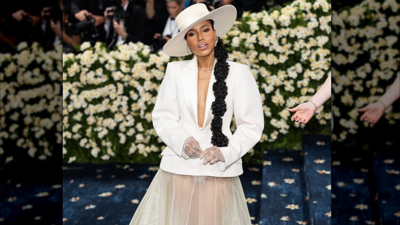 Kerry Washington posant au Met Gala 2025 portant un chapeau blanc, un haut blanc avec un décolleté plongeant et une jupe en tulle transparent.