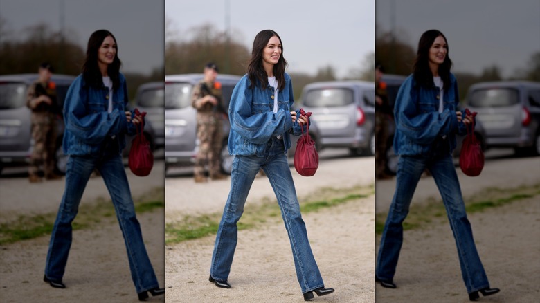 Une femme marchant dans un jean bootcut et une veste en jean surdimensionnée