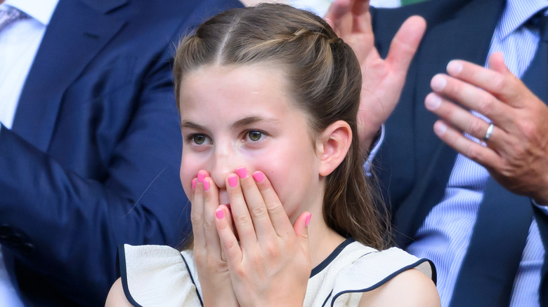 La princesse Charlotte photographiée à Wimbledon en 2025 avec ses mains sur la bouche et portant du vernis à ongles rose.