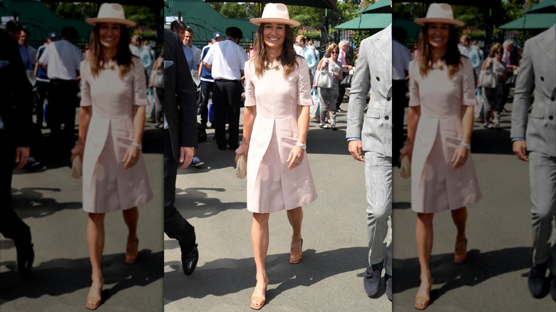 Pippa Middleton portant une robe rose clair et un chapeau fedora marchant à Wimbledon en 2019.