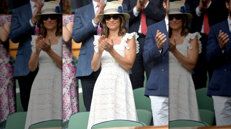 Pippa Middleton applaudissant vêtue d'une robe blanche avec des lunettes de soleil et un fedora à Wimbledon en 2018.