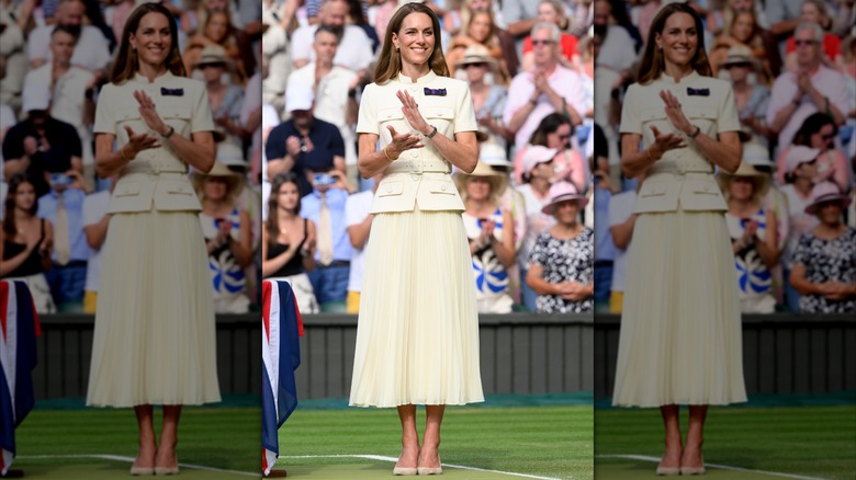 Kate Middleton applaudissant et portant une jupe plissée de couleur crème et un haut ceinturé boutonné à Wimbledon en 2025.