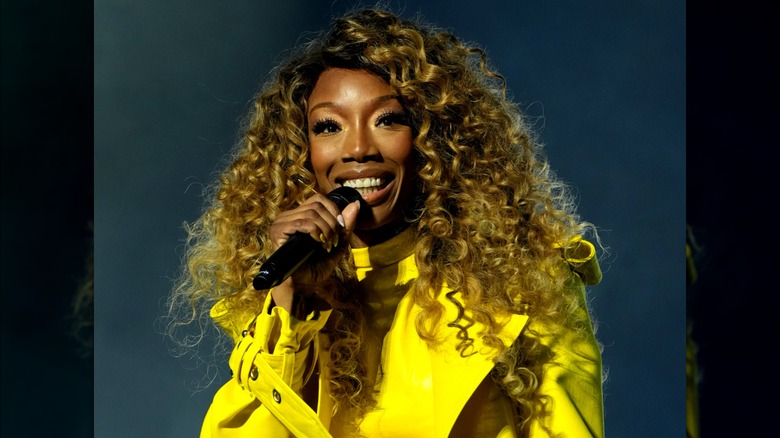 Brandy portant un haut jaune vif et des boucles blondes miel