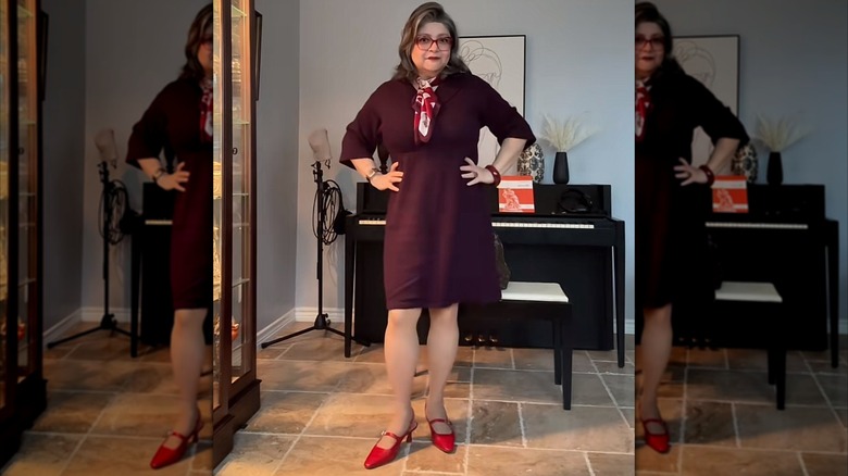 Une femme avec une robe violet foncé, des chaussures rouge vif et un foulard imprimé.