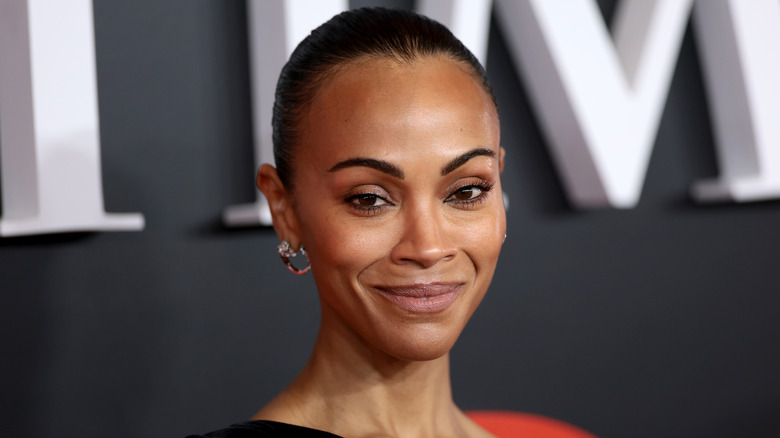 Zoe Saldana dans une robe noire avec un chignon lissé dans le dos.