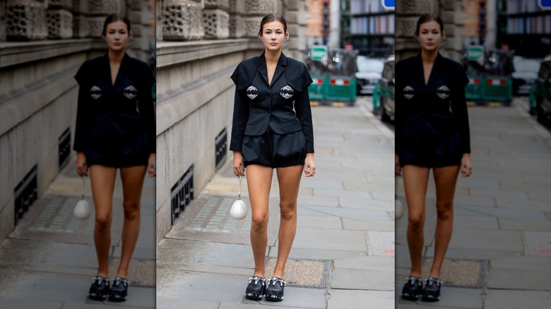 Une femme portant des Crocs éblouis et un blazer noir