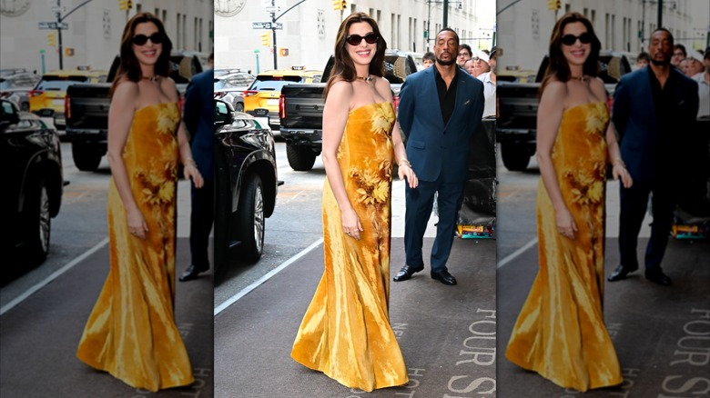 Anne Hathaway sourit dans une robe jaune bustier