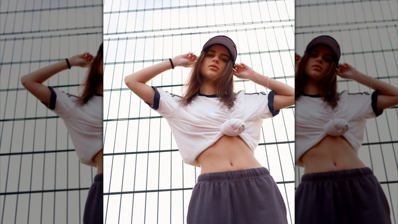 Une femme posant dans un crop top noué blanc et bleu marine et un pantalon de survêtement.