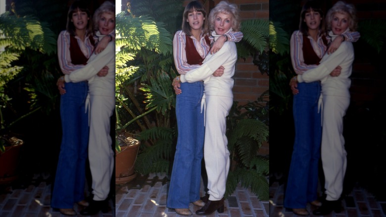 Jamie Lee Curtis portant un jean évasé, une chemise rayée et un gilet marron avec Janet Leigh portant une tenue blanche en 1979.