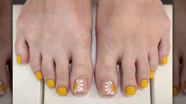 Gros plan sur une pédicure jaune moutarde avec un bout en forme de marguerite