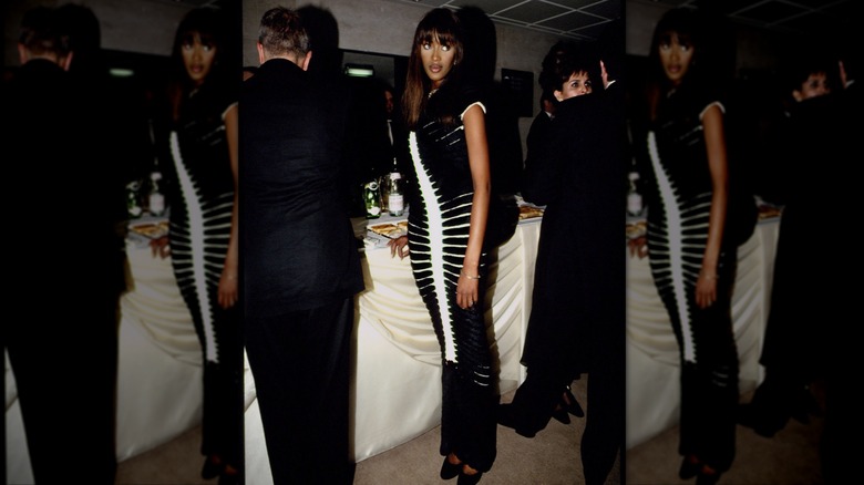 Naomi Campbell portant une robe longue illusion noire et blanche lors d'un événement.