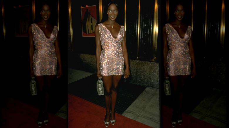 Naomi Campbell porte une mini-robe scintillante à col bénitier.