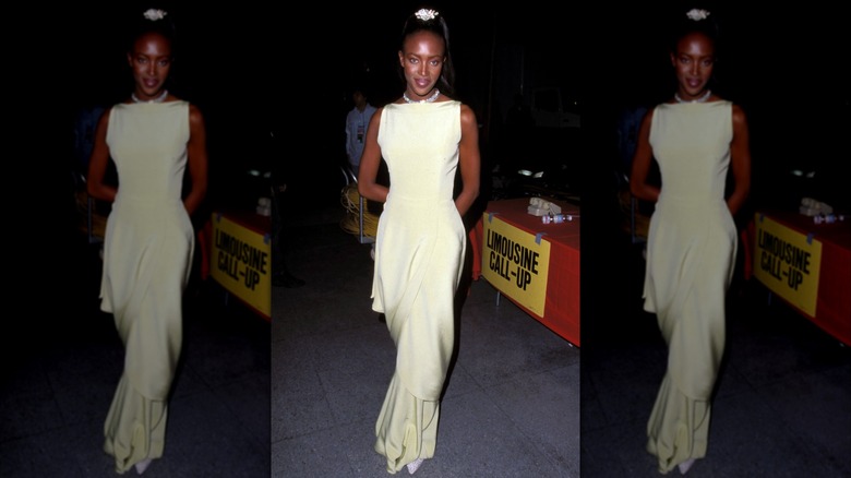 Naomi Campbell porte une robe jaune clair à col bateau.