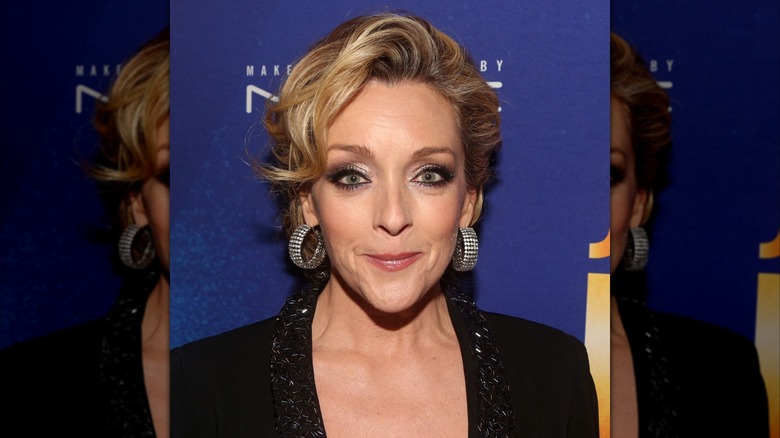 Jane Krakowski avec un chignon bouclé et de grandes boucles d'oreilles tendance