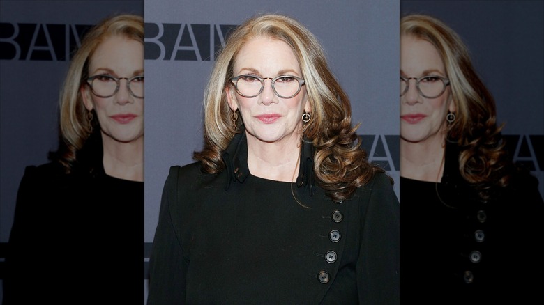 Melissa Gilbert sourit avec des lunettes rondes et un blazer noir