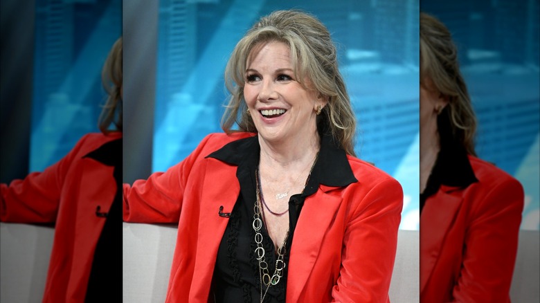 Melissa Gilbert sourit avec une coiffure volumineuse et un blazer rouge
