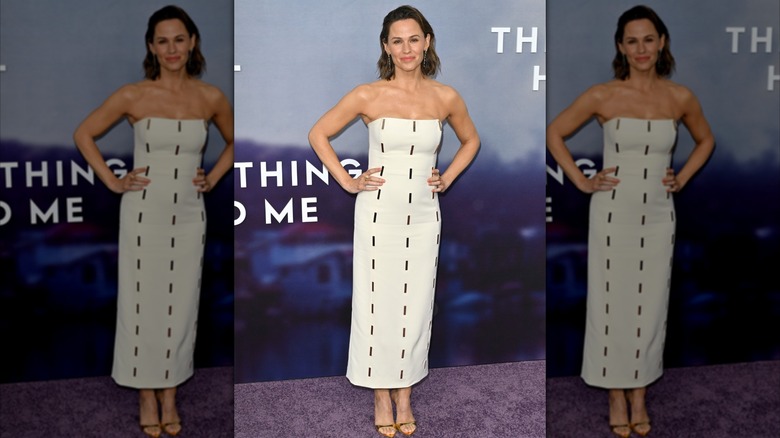 Jennifer Garner, les mains sur les hanches, vêtue d'une robe bustier blanche avec des motifs de tirets lors d'un événement sur le tapis rouge.