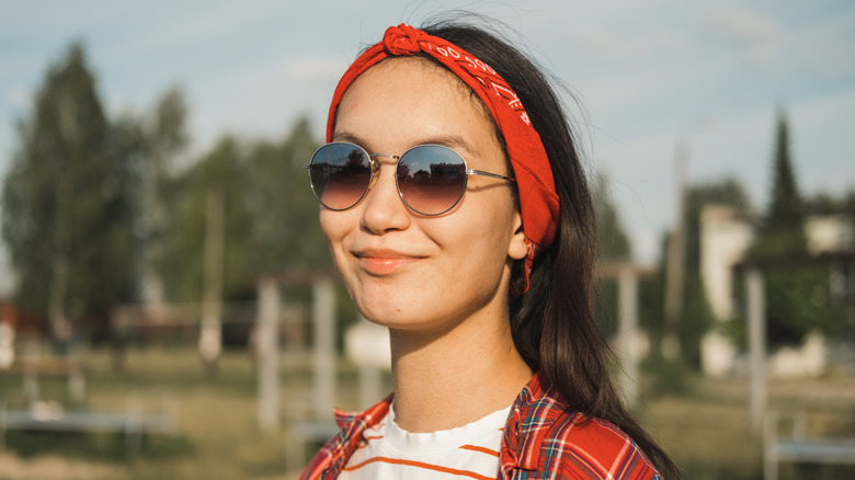 Une femme accessoirisant avec des lunettes de soleil et un bandana