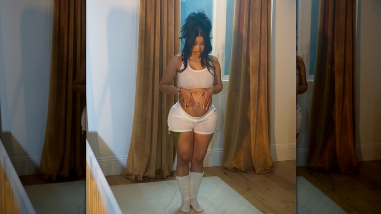 Cardi B tient son baby bump dans un deux pièces blanc