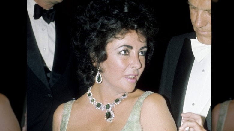 Elizabeth Taylor porte une robe verte et un tour de cou en cristal émeraude