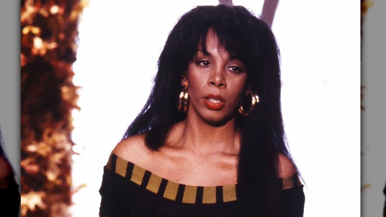 Donna Summer se produit avec des créoles dorées et une jupe dorée.