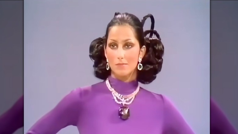 Cher portant une robe violette et un collier en verre saphir