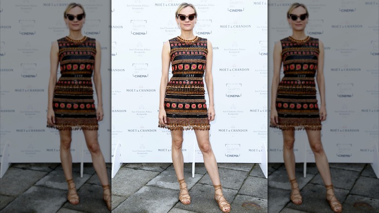 Diane Kruger lors d'un événement portant une mini-robe à rayures complexes avec des lunettes de soleil.