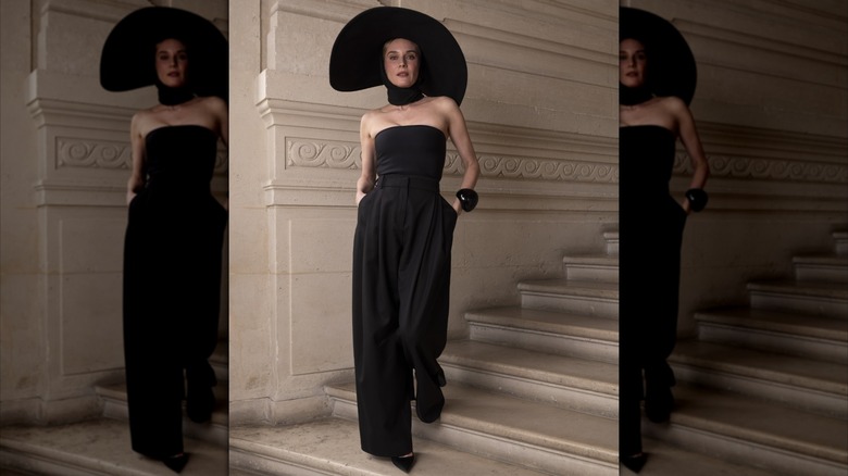 Diane Kruger porte une combinaison noire sans bretelles avec un tour de cou noir et un chapeau noir à larges bords.