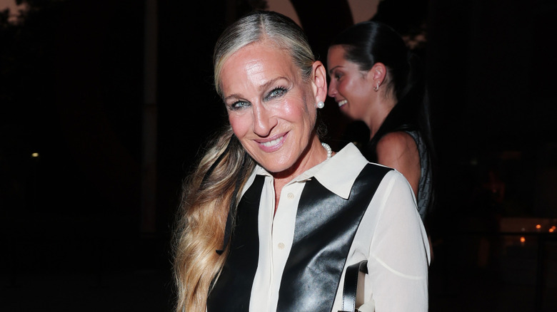 Sarah Jessica Parker posant lors d'un événement portant un haut noir et blanc avec ses cheveux en queue de cheval basse.