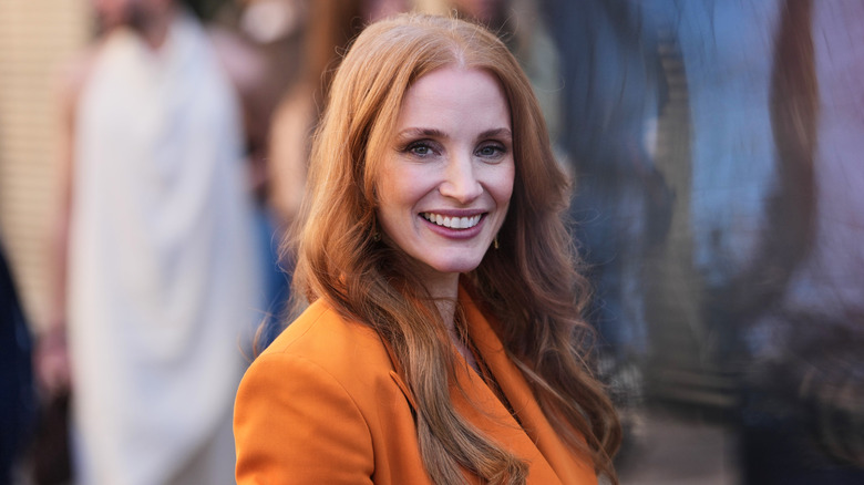 Jessica Chastain posant lors d'un événement vêtue d'une robe blazer orange.