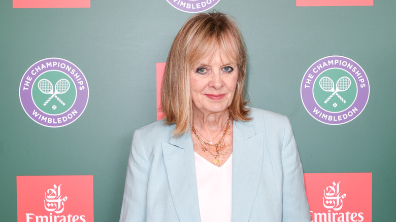 Twiggy posant lors d'un événement en 2025 portant un haut blanc et un blazer bleu clair.
