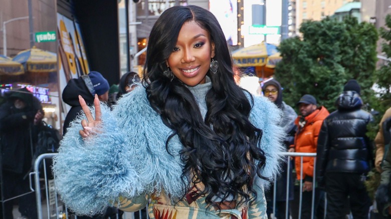 Brandy portant un pull bleu poudré moelleux et de longues vagues sombres